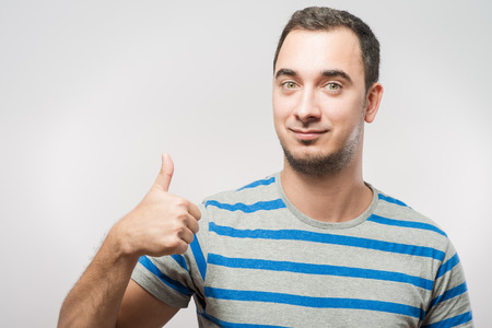 Handsome man holds his thumbs upの写真素材