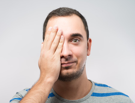 Young Caucasian man hiding his face with handの写真素材