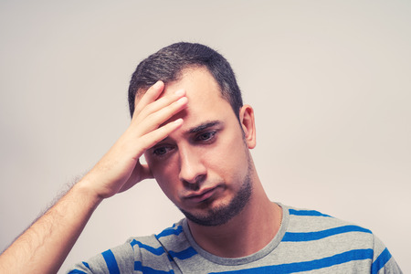 Depressed young man  holding head in handsの写真素材