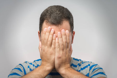 Young Caucasian man hiding his face with handの写真素材
