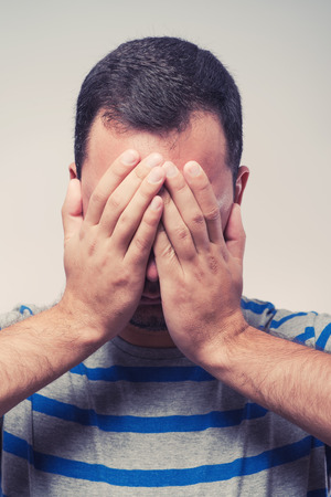 Young Caucasian man hiding his face with handの写真素材