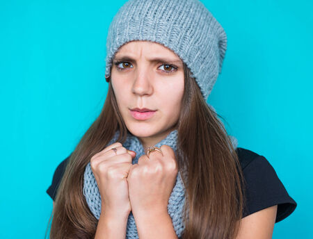 freezing young woman hiding behind her scarf in snowfallの写真素材