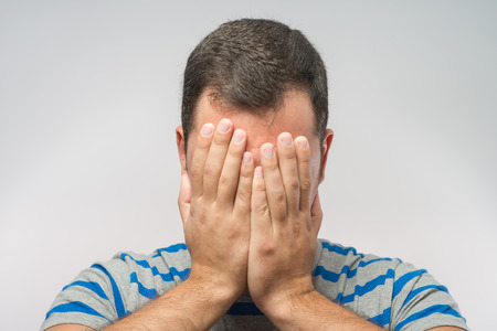 Young Caucasian man hiding his face with handの写真素材