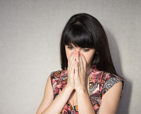 Portrait of young woman covering her face with hands.の写真素材