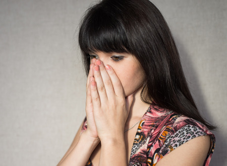 Portrait of young woman covering her face with hands.の写真素材