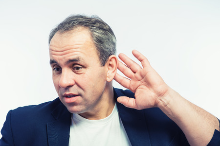 Businessman holds his hand near his ear and listening somethingの写真素材