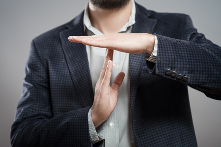 young businessman showing time out sign with hands against