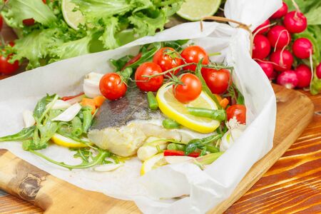 Cod with lemon slices and vegetables wrapped in baking parchment. Preparing food. Macro, selective focusの写真素材