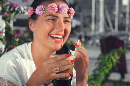 Happy young woman drinking iced coffee in restaurant.  Focus on the glass of ice  coffeeの写真素材