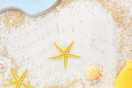 Holiday beach frame. Sea shells, fishing net and  suntan lotion on a wooden background, Top view, vintage toned image, blank spaceの写真素材