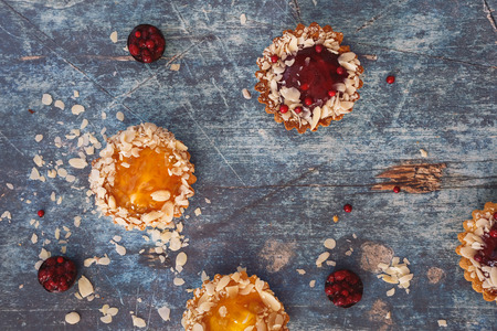 Assorted mini tarts of different sizes on rustic table. Top view, blank space