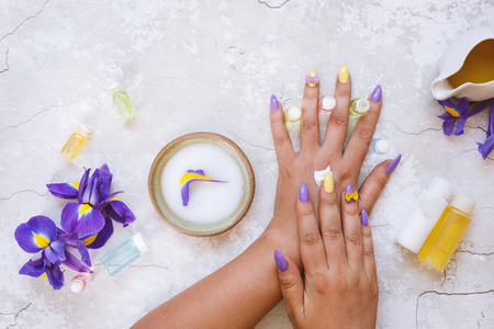 Iris natural skincare cosmetic. Women's hands apply cream. Top view, blank space, rustic backgroundの写真素材