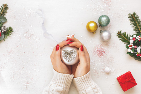 Woman Holding Christmas Ornaments. Unrecognizable woman holding a Christmas bauble, top view, flat layの写真素材