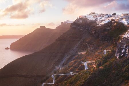 Sunset on the Greek Island of Santorini,with colorful  warm light and clouds over the town. The view...