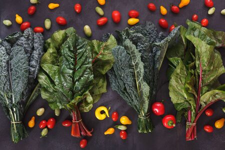 Fresh leafy greens, cherry tomatoes and chili on rustic surface. Farmers market, dieting and nutrition concept.  Top view, blank space, flat layの写真素材