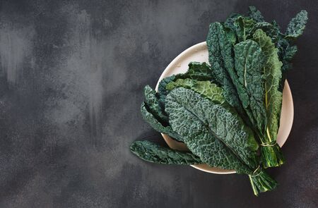 Fresh  Tuscan kale leaves on a white plate and on rustic dark background. Top view, blank spaceの写真素材