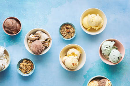 Various ice cream desserts in bowls on rustic blue background, Top view, blank spaceの写真素材