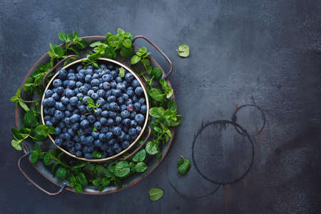 Plate of blueberries. Plate full of  ripe blueberries placed on black  rustic background. Top view, blank spaceの写真素材