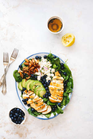 Organic blueberry walnut almond and feta salad with grilled chicken and spinach on white rustic...