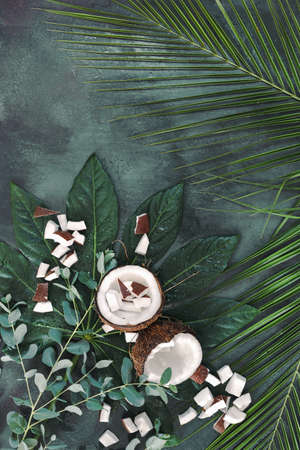 Natural spa still life  with fresh coconut and collection of different green leaves on rustic...