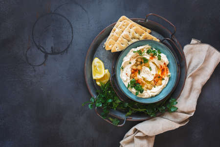 Delicious homemade chickpea hummus sprinkled with chickpeas and parsley served with pita bread. Top...