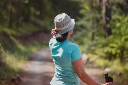 Mature woman walking in pine forest alone . Sunshine shining through the forest. Concept of travel...