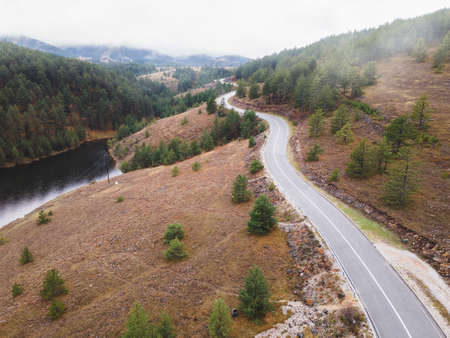 Aerial rural landscape with curving road, forest and lake. Nature outdoors travel destination,...