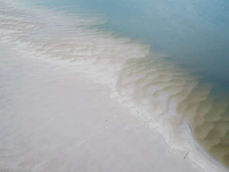 The sandy bank of the Danube River near the city of Novi Sad, details. Background of sand ripples and water on beach at low tide.の写真素材