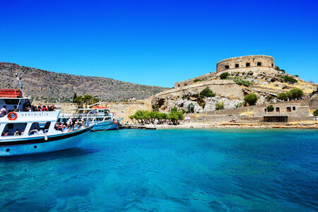 SPINALONGA, GREECE - MAY 14: The motor yachts with tourists are near Spinalonga island on May 14, 2014 in Spinalonga, Greece. Up to 16 mln tourists is expected to visit Greece in year 2014.のeditorial素材