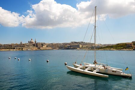 The view on Valletta and sail yacht with Ukrainian flag in sunset, Sliema, Maltaの写真素材