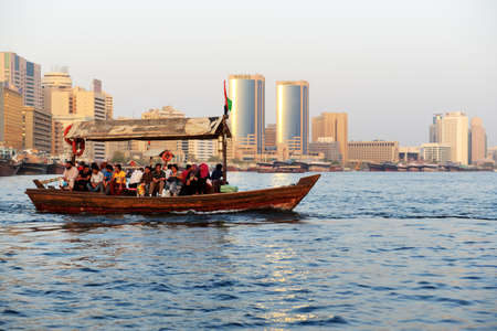 DUBAI, UAE - SEPTEMBER 10: The traditional Abra boat with people in Dubai Creek on September 10, 2013 in Dubai, United Arab Emirates. The Abra is cheapest transport in Dubaiのeditorial素材