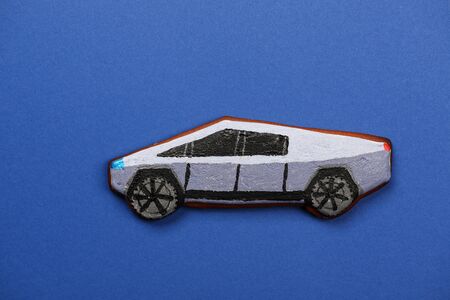 The hand-made eatable gingerbread Tesla Cybertruck electric car on blue background
