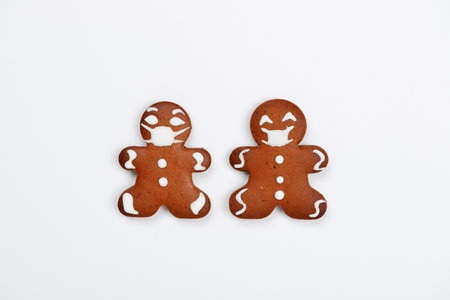 The hand-made eatable gingerbread little men with face masks on white backgroundの写真素材