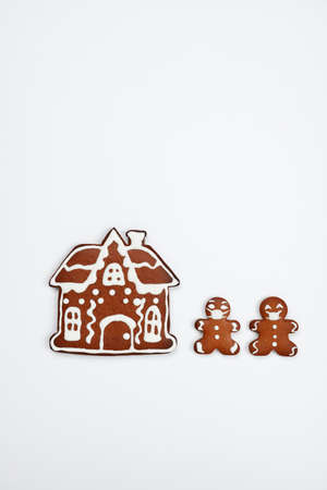 The hand-made eatable gingerbread house, little men with face masks on white background