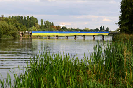 BILA TSERKVA, UKRAINE - AUGUST 22: The view on Ukrainian National Flag dedicated to Ukrainian Independence Day wich lays on wooden bridge over Ros river on August 22, 2020 in Bila Tserkva, Ukraine.のeditorial素材