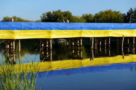 BILA TSERKVA, UKRAINE - AUGUST 22: The view on Ukrainian National Flag dedicated to Ukrainian Independence Day wich lays on wooden bridge over Ros river on August 22, 2020 in Bila Tserkva, Ukraine.のeditorial素材