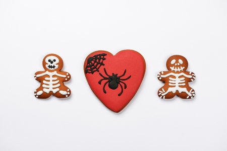 The hand-made eatable gingerbread heart with spider and sceletons on white backgroundの写真素材