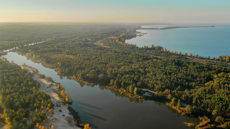 Beautiful river flowing along the forest shooting from a birds eye viewの写真素材