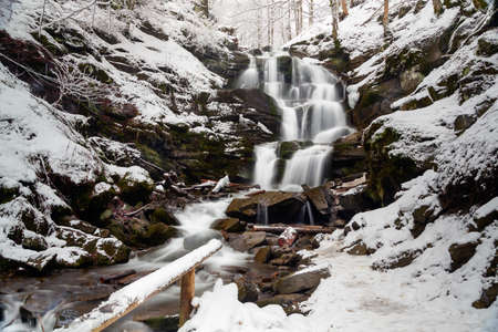 Scenic view of the beautiful Shypit waterfall in the Carpathian mountains, winter landscape. Popular tourist attraction, nature travel background suitable for wallpaper or coverの写真素材