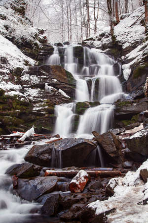 Scenic view of the beautiful Shypit waterfall in the Carpathian mountains, winter landscape. Popular tourist attraction, nature travel background suitable for wallpaper or coverの写真素材
