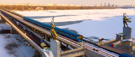 Aerial drone view. The Kiev metro train travels across the bridge through the Dnieper river. Winter sunny morning.の写真素材