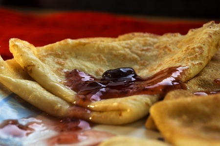 Pancakes with cherry jam and cutlery on a red backgroundの写真素材