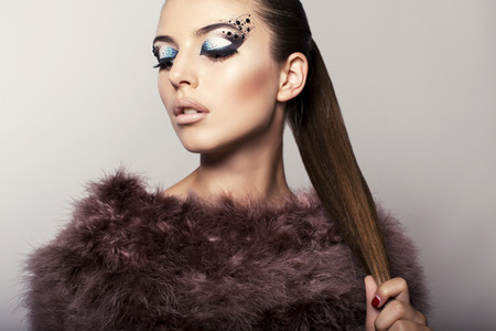 fashion studio photo of beautiful girl with extravagant eyes makeup and furの写真素材