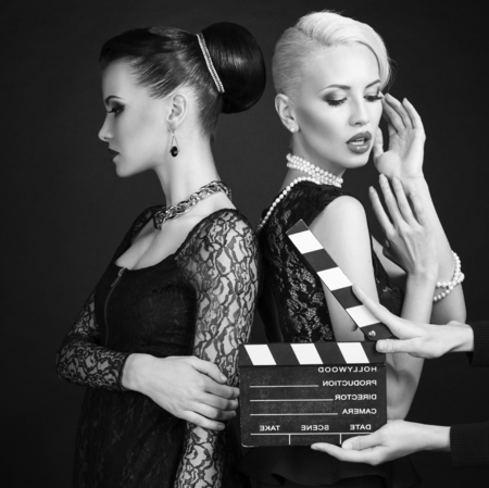 fashion studio photo of beautiful women in retro style posing with cinema clappe rboardの写真素材