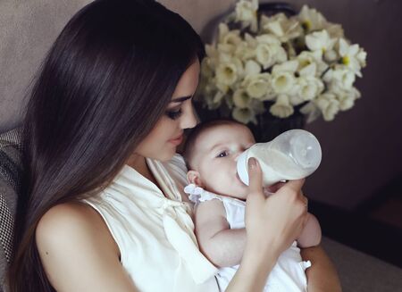 tender photo of beautiful mother with luxurious dark hair and her cute little babyの写真素材