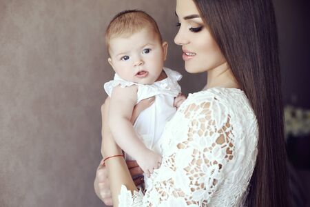tender photo of beautiful mother with luxurious dark hair and her cute little babyの写真素材