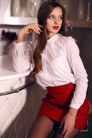 fashion studio photo of beautiful young woman with dark hair in elegant dress posing in bedroomの写真素材