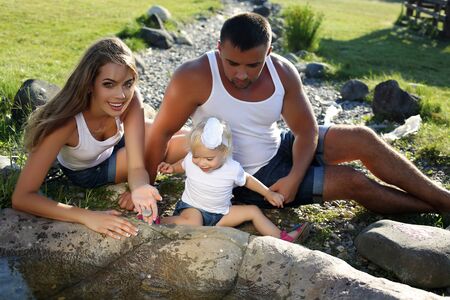 fashion outdoor photo of beautiful family having fun with their cute little daughter in summer gardenの写真素材
