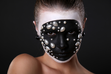 fashion studio portrait of young girl with black and white art pattern on her face.Halloween styleの写真素材