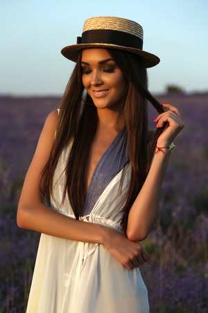 fashion outdoor photo of gorgeous sensual woman with dark long hair in elegant outfit posing at blossom lavender fieldの写真素材